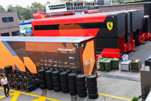A McLaren transporter next to Ferrari trucks in the paddock