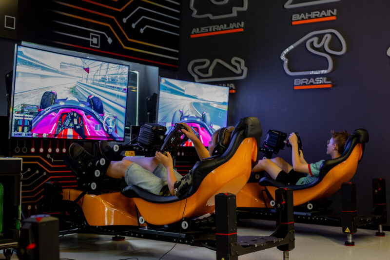 Grupa pracowników firmy po przyjęciu pucharów, w tracie wyścigów na symulatorach Formuły 1 w Warszawskim centrum rozrywki A1Karting.